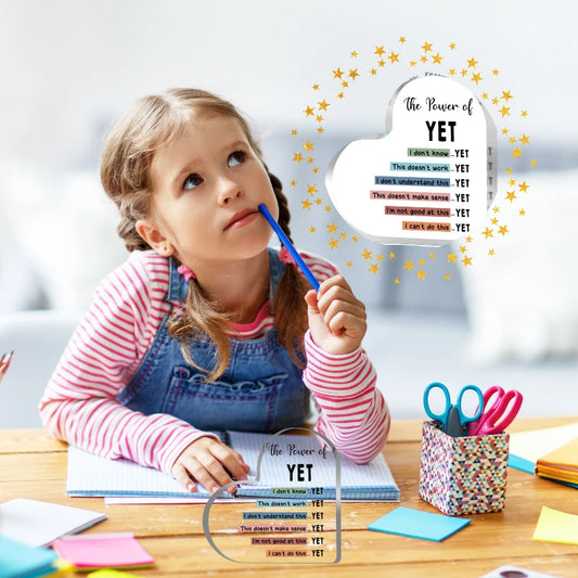 Child at a desk with educational materials and an acrylic heart with 'The Power of Yet' text.