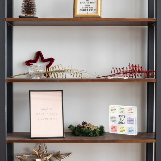 Decorative shelf with various items including a framed quote, acrylic plaque, and decorative branches.