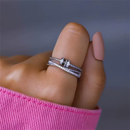 Close-up of a hand wearing the silver ring with a pink sleeve against a gray background