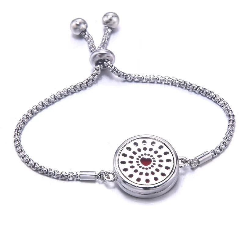 Silver bracelet with a red pad featuring a heart design with dots around it on a white background
