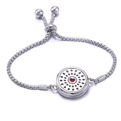 Silver bracelet with a red pad featuring a heart design with dots around it on a white background