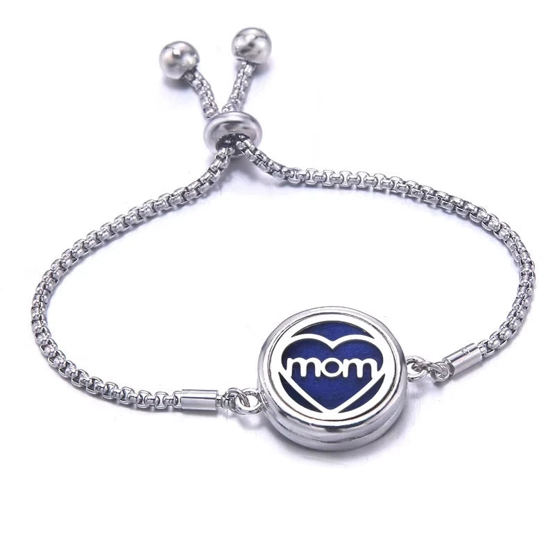 Silver bracelet with a blue pad featuring a heart-shaped charm displaying the word 'mom' on a white background