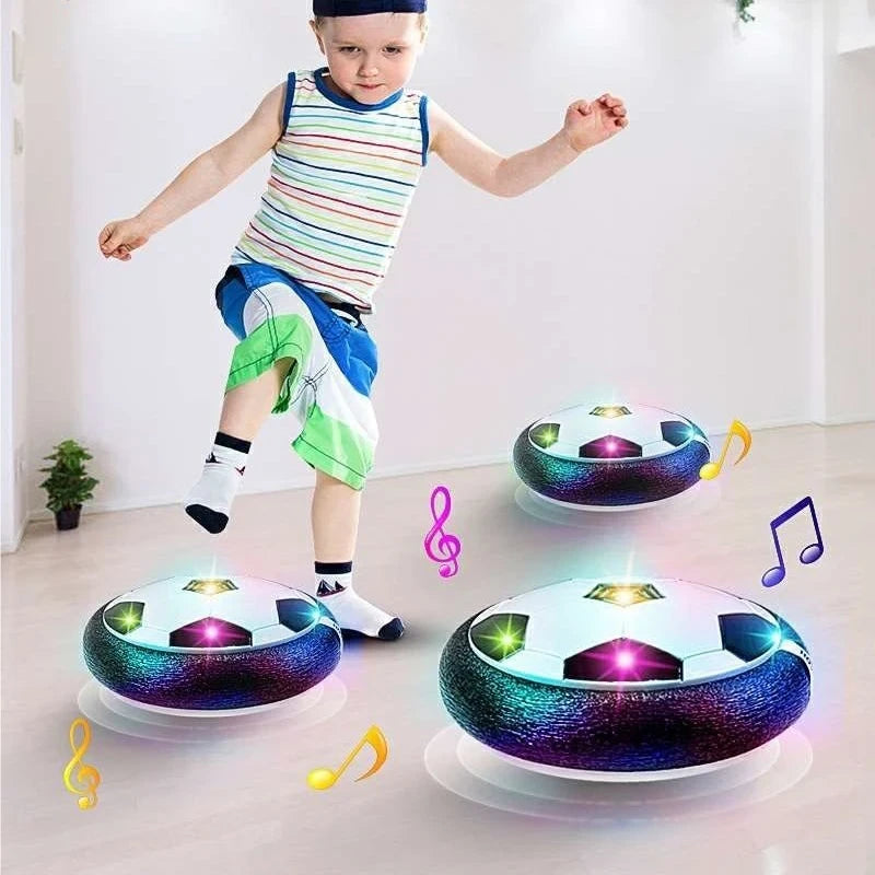 Child playing with hover soccer ball on a light wooden floor.