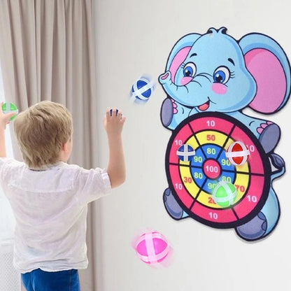 Child throwing sticky balls at a target board shaped like an elephant mounted on a wall.