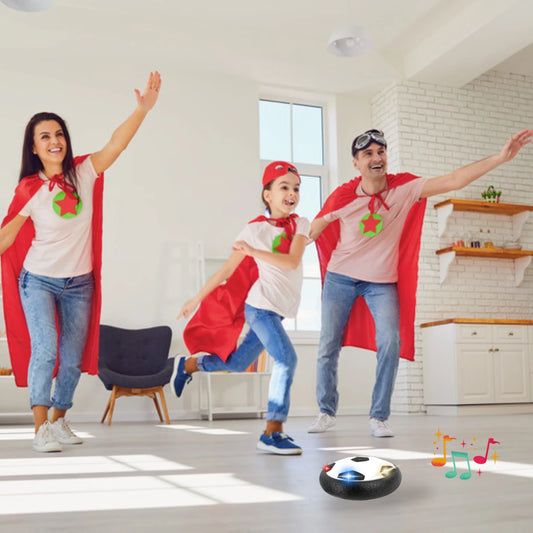 Family of three in superhero costumes playing with a hover soccer ball on a light-colored floor.