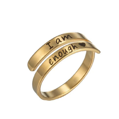 Gold ring with 'I am enough' laser etched on, on a white background