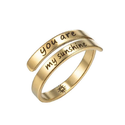 Gold ring with 'you are my sunshine' laser etched on, on a white background