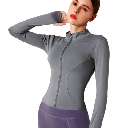 Woman wearing a grey zip up thumb hole jacket and purple leggings showing the front view against a white background 