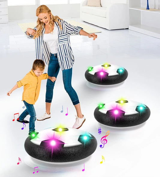 Woman and child playing with hover soccer ball on a white floor.