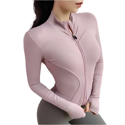 Woman wearing a pink zip up thumb hole jacket and gray leggings against a white background