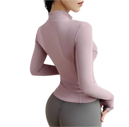 Woman wearing a pink zip up thumb hole jacket and gray leggings showing the back right side view against a white background 