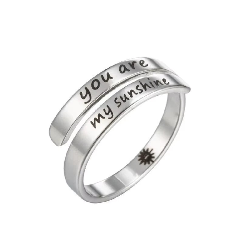 Silver ring with 'you are my sunshine' laser etched on, on a white background