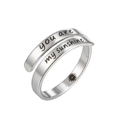 Silver ring with 'you are my sunshine' laser etched on, on a white background