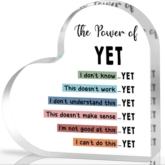 Heart-shaped sign with motivational phrases like 'The Power of Yet' on a white background