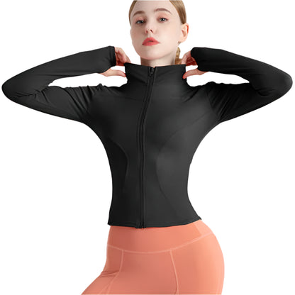 Woman wearing a black zip up thumb hole jacket and light orange leggings showing the front view against a white background 