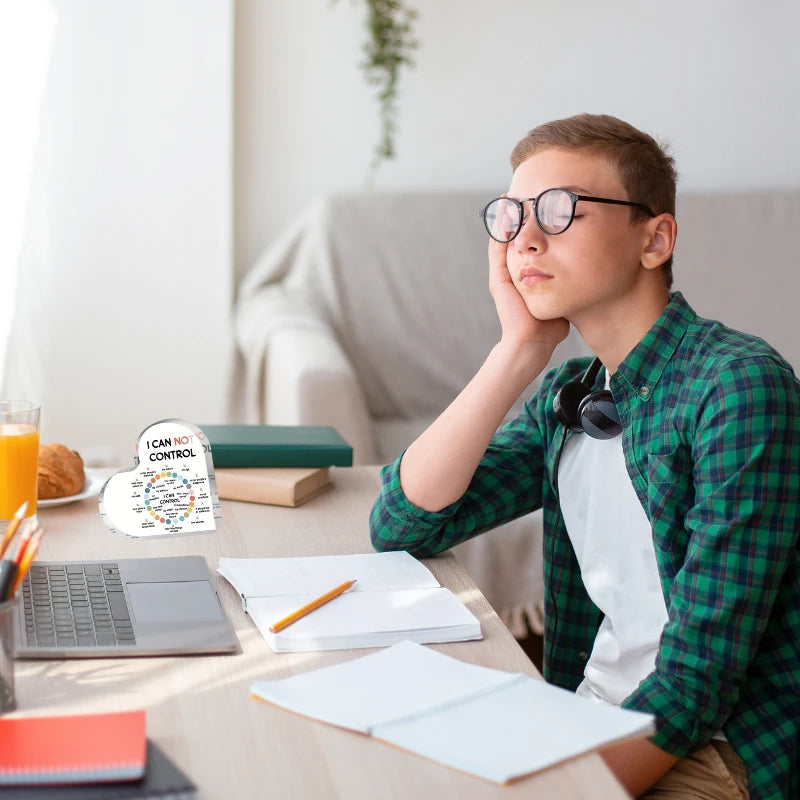 Person sitting at a desk with a laptop, books, and a glass of orange juice.