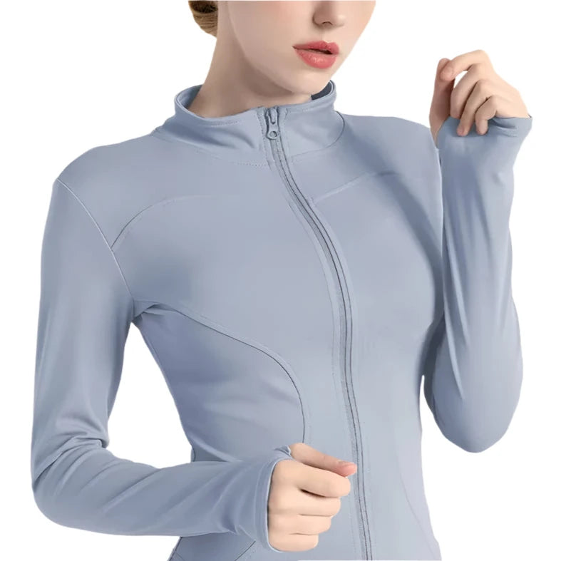 Close-up of a woman wearing a light blue zip up thumb hole jacket  against a white background 