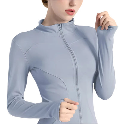 Close-up of a woman wearing a light blue zip up thumb hole jacket  against a white background 