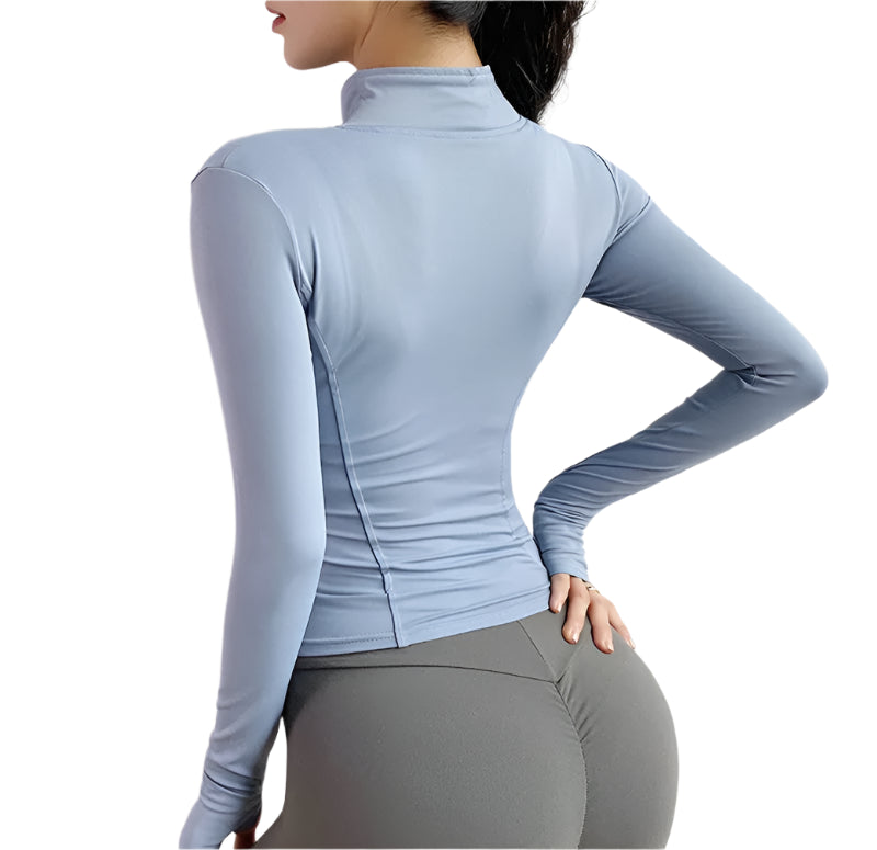 Woman wearing a light blue zip up thumb hole jacket and gray leggings showing the back against a white background 