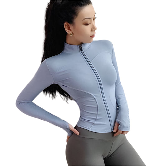 Woman wearing a light blue zip up thumb hole jacket and gray leggings against a white background