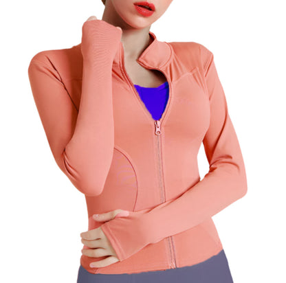 Woman wearing a light orange zip up thumb hole jacket and purple leggings showing the front view against a white background 