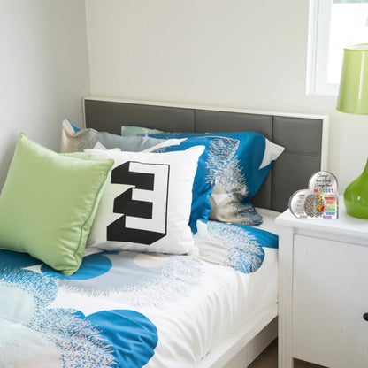 Bedroom with colorful bedding and pillows on a bed with a gray headboard.