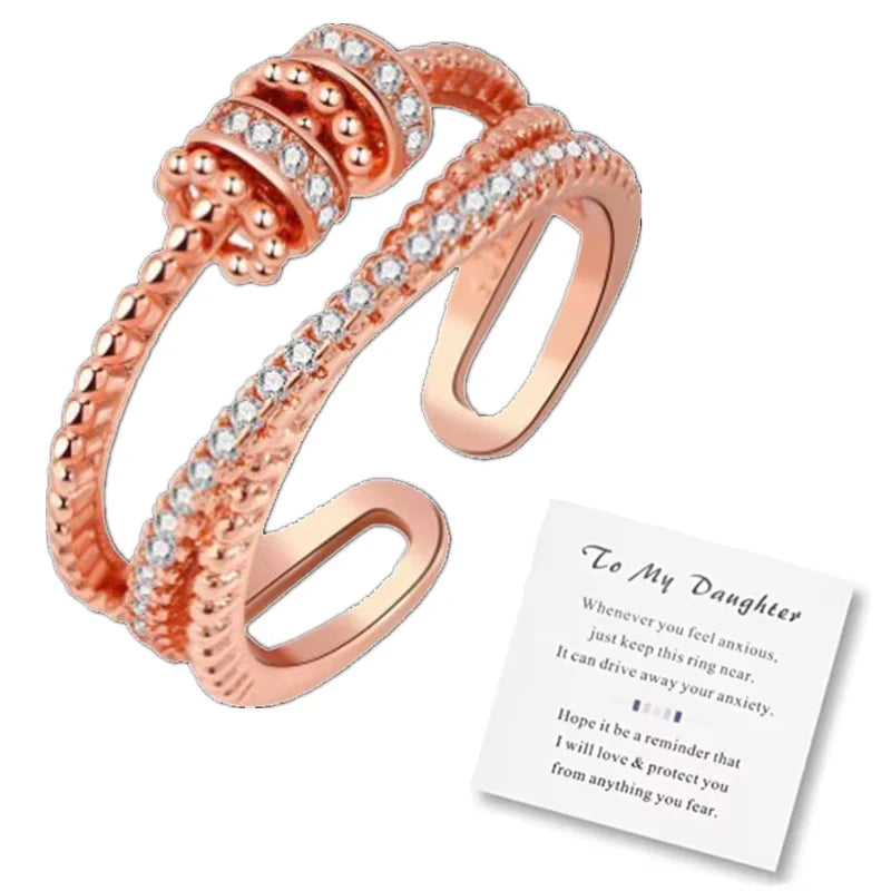 Rose gold ring with embedded stones and a card on a white background