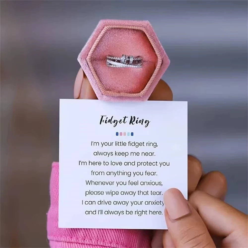 Fidget ring in a pink hexagonal box held by a hand with a sentimental card.