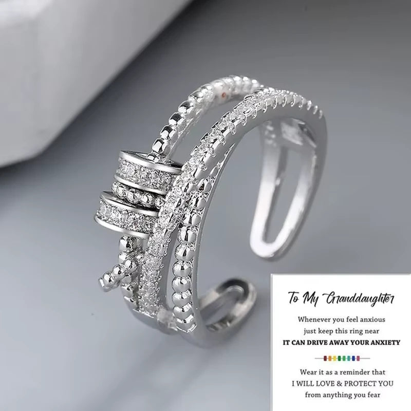 Silver ring with spinner design accents on a gray surface, accompanied by a sentimental message.